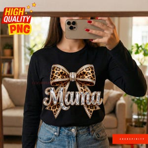 May include: Black long-sleeve shirt featuring a leopard print bow design with rhinestone accents and the word "Mama" in a rhinestone font. The shirt has the text "High Quality PNG" in the upper left corner.