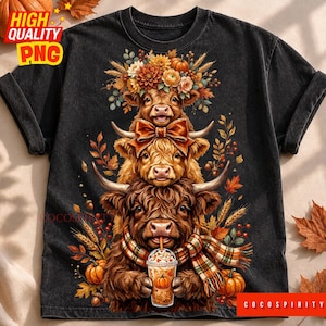 May include: A black t-shirt featuring a graphic of three stacked Highland cows. The top cow wears a floral crown, the middle cow has a bow, and the bottom cow wears a plaid scarf while holding a pumpkin spice latte. Autumn leaves and pumpkins surround them.
