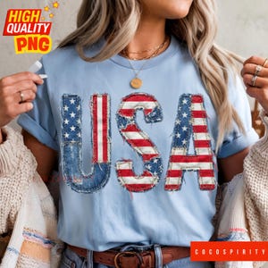Könnte beinhalten: Hellblaues T-Shirt mit dem Wort "USA" in einem Used-Denim-Design, das die Sterne und Streifen der amerikanischen Flagge zeigt. Das Shirt hat hochgekrempelte Ärmel und einen braunen Gürtel. Der Text "HIGH QUALITY PNG" befindet sich oben links.