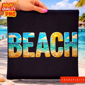 Op de afbeelding: Zwart rechthoekig bord met het woord "BEACH" in kleurrijke letters in mozaïekstijl. De letters hebben een strandthema met blauwe lucht, oceaangolven en een gele zon. Het bord wordt vastgehouden door een persoon met roze nagellak.