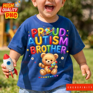 Könnte beinhalten: Ein marineblaues T-Shirt mit dem Text "PROUD AUTISM BROTHER" in bunten Buchstaben. Ein Teddybär, der eine Rakete hält, ist auf das Shirt gedruckt. Das Kind hält auch eine Spielzeugrakete.