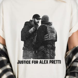 May include: Cream-colored t-shirt featuring a black and white image of two individuals in tactical gear. The text "JUSTICE FOR ALEX PRETTI" is printed in black across the bottom of the shirt.
