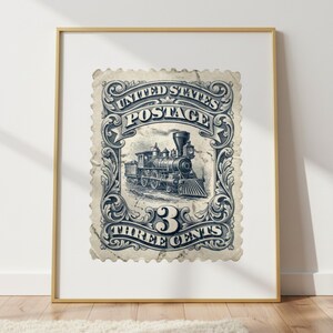 May include: Framed vintage postage stamp print featuring a detailed illustration of a steam train. The stamp reads "United States Postage" and "Three Cents" in a decorative border. The print is in shades of blue and white.