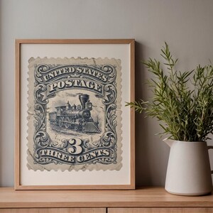 May include: Framed vintage United States postage stamp print. The print features a detailed illustration of a steam train, with the text "UNITED STATES POSTAGE" and "3 THREE CENTS" in a decorative border. The print is framed in a light wood frame.