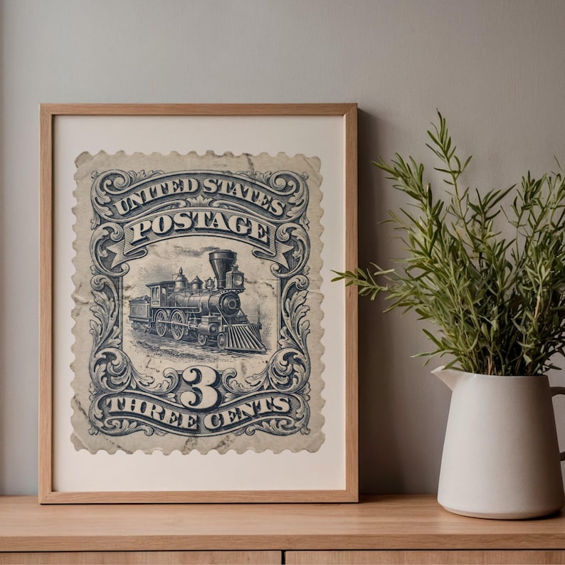 May include: Framed vintage United States postage stamp print. The print features a detailed illustration of a steam train, with the text "UNITED STATES POSTAGE" and "3 THREE CENTS" in a decorative border. The print is framed in a light wood frame.
