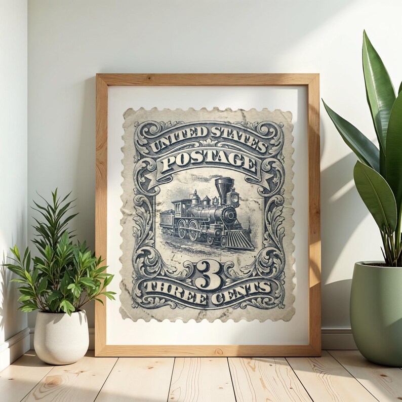May include: Framed vintage print of a United States postage stamp featuring a detailed illustration of a steam train. The stamp is in shades of blue and white, with the text "UNITED STATES POSTAGE" and "THREE CENTS". The frame is made of light-colored wood.