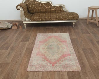 Puede incluir: Una alfombra vintage de color rosa claro y crema con un patrón floral descolorido. La alfombra está colocada sobre un suelo de madera.