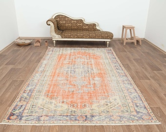 Pode incluir: Um tapete de estilo vintage com um padrão desbotado em laranja, creme e azul. O tapete tem um visual desgastado e é perfeito para adicionar um toque de estilo boêmio a qualquer cômodo.