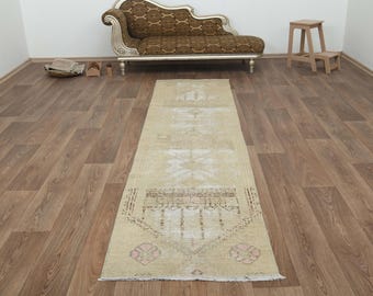 May include: A beige runner rug with a faded floral pattern. The rug has a distressed look and is made of natural fibers.