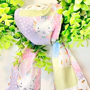 May include: A handmade Easter-themed fabric mask and scarf set. The mask and scarf feature a patchwork design with pastel colors, floral patterns, and a bunny face. The scarf is approximately 40 inches long.