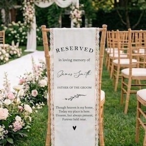 Peut inclure: Un panneau "Réservé" pour une cérémonie de mariage. Le tissu blanc est drapé sur une chaise en bois et bordé de dentelle. Le texte indique "RESERVED" et "in loving memory of James Smith, Father of the Groom".