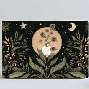 Op de afbeelding: Laptop skin met een botanisch ontwerp. Het kunstwerk bevat een Apple-logo, een volle maan, sterren en een halve maan. Bloemen- en bladelementen in groen, beige en goud staan tegen een zwarte achtergrond.