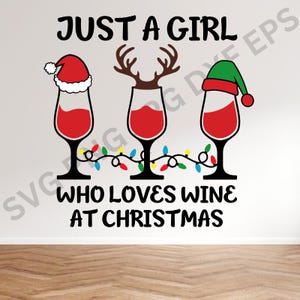 May include: A white background with the text "Just a girl who loves wine at Christmas". There are three wine glasses with red wine, each topped with a different holiday hat: a Santa hat, a reindeer antler headband, and a green elf hat. A string of colorful Christmas lights is wrapped around the glasses.