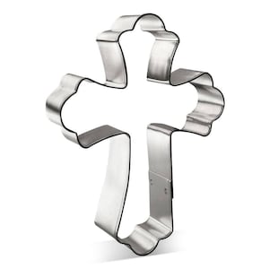 May include: A silver metal cookie cutter shaped like a cross with a decorative design.