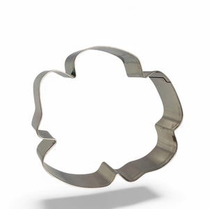 Könnte beinhalten: Ein silberner Ausstecher aus Metall in Form einer Blume mit fünf Blütenblättern.