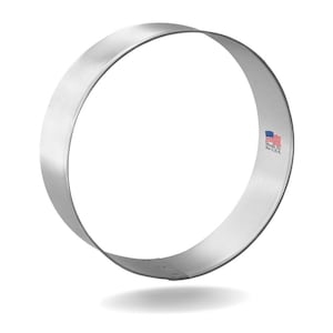 May include: A circular, stainless steel cookie cutter with a brushed finish. The cutter is a complete ring shape, ideal for baking. The words "Made in the USA" are printed on the side, along with a small American flag.