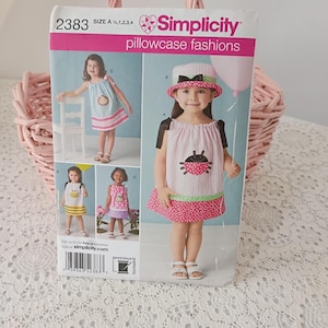 May include: Simplicity pillowcase fashions sewing pattern. The pattern features multiple children's dresses with various designs, including a ladybug, bee, and striped patterns. The pattern is size A 1/2, 1, 2, 3, 4.