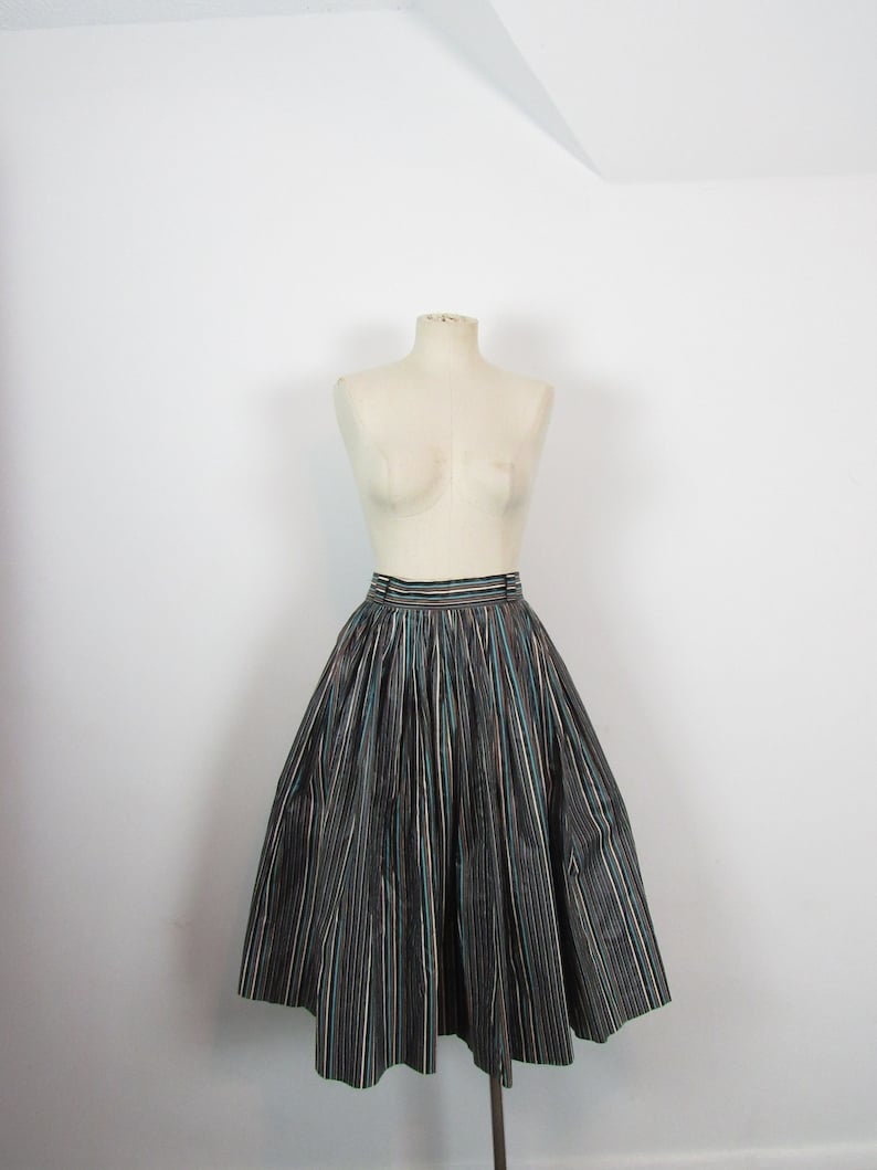 May include: A black and white striped skirt with a teal stripe. The skirt is full and has a gathered waist.