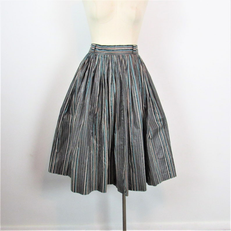 May include: A black and white striped skirt with a hint of blue and pink. The skirt is full and has a gathered waist.