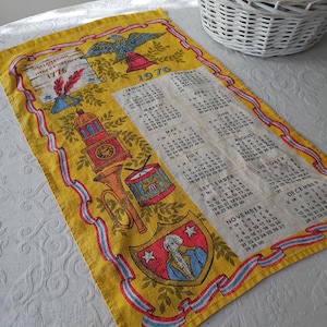 May include: A vintage yellow kitchen towel with a calendar for the year 1976. The towel features patriotic imagery, including an eagle, bell, and a depiction of George Washington. The design is framed with red, white, and blue ribbons.