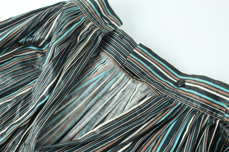 May include: A black, brown, and teal striped skirt with a button closure at the back.