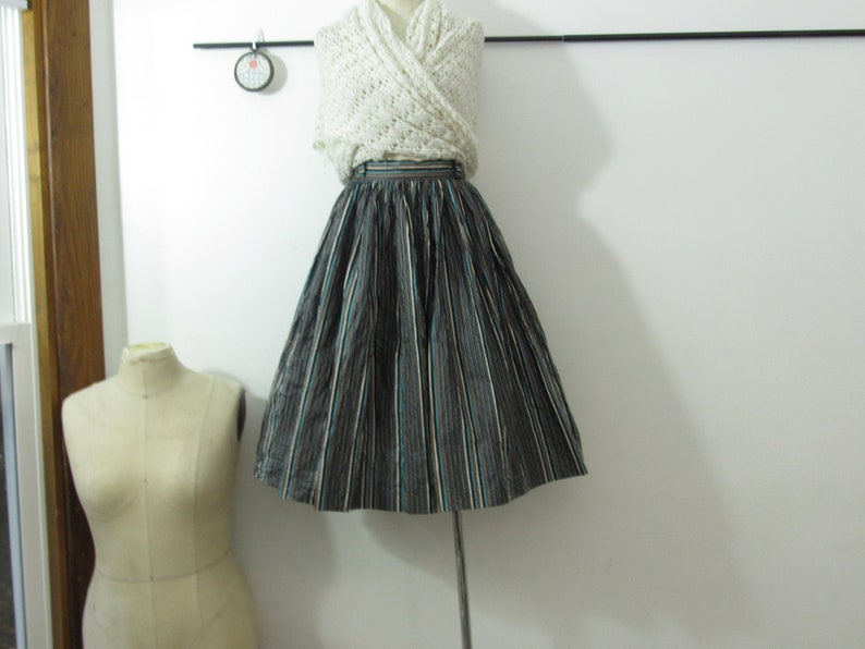 May include: A black and white striped skirt with a teal stripe. The skirt is full and has a high waist.