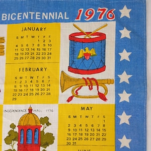 May include: A vintage 1976 Bicentennial calendar towel. The design features a drum, trumpet, and Independence Hall illustrations. The calendar includes the months of January, February, and May, with a blue and yellow color scheme.