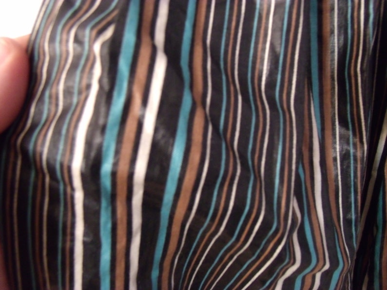 May include: Close-up of a fabric with a striped pattern in black, white, brown, and teal.