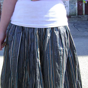 May include: A black and white striped skirt with a white tank top. The skirt has a gathered waist and is made of a lightweight fabric.