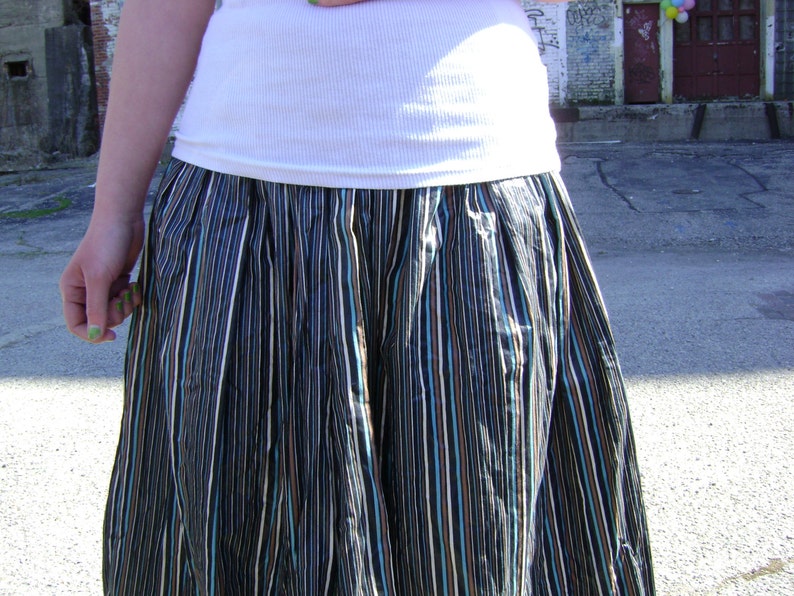 May include: A black and white striped skirt with a white tank top. The skirt has a gathered waist and is made of a lightweight fabric.