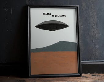May include: A black framed poster with the text "SEEING IS BELIEVING" in white. The poster features a black and white illustration of a flying saucer over a brown and green landscape.