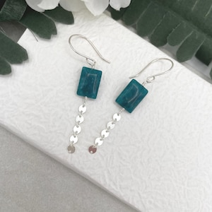 May include: Teal green rectangular stone earrings with a silver chain of small round links.