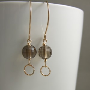 May include: A pair of gold earrings with a smoky quartz gemstone and a gold circle dangle.