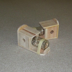 May include: Two wooden bird feeders with clear glass jars attached. The feeders are made of unfinished wood and have a simple design.