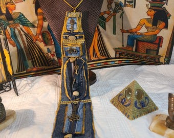 May include: A denim tie with gold accents and various embellishments, including a key, an eye symbol, and a miniature jacket. The tie is displayed on a mannequin with a gold chain necklace. The text "denim24/7" is visible on the tie.