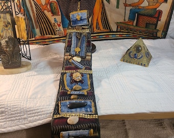 May include: A unique, handcrafted necktie with denim and stone embellishments. The tie features a black and burgundy patterned fabric, with decorative elements including small stones, gold trim, and a Stacy Adams label.
