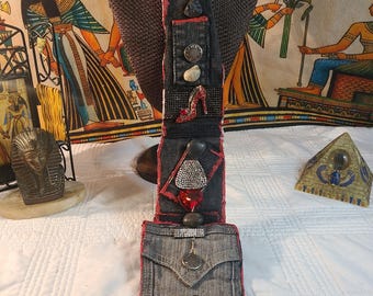 May include: A handcrafted denim and red fabric pendant necklace with various embellishments. The necklace features a silver chain, a sunburst pendant, and decorative elements like a red high-heeled shoe, stones, and a large red oval gem.