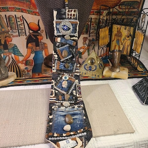 May include: A unique, handmade necktie with a patchwork design. The tie features denim, patterned fabric, and embellishments including stones and a silver chain. The Givenchy label is visible at the tip. The tie is displayed on a mannequin head.