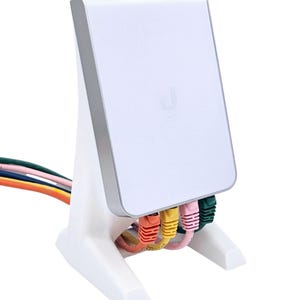 Op de afbeelding: Een wit netwerkapparaat met een zilveren rand en een witte standaard. Het apparaat heeft meerdere gekleurde Ethernet-kabels aangesloten. Het apparaat heeft de letter "U" op de voorkant gedrukt.