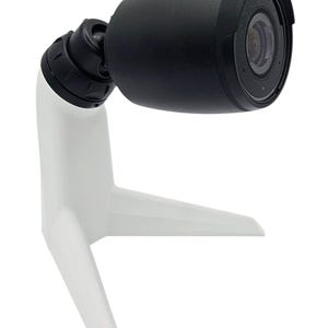 Op de afbeelding: Een zwarte beveiligingscamera met een witte standaard. De camera is gemonteerd op een zwenkarm en heeft een lens met een zwarte ring.