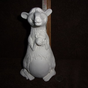May include: A white ceramic figurine of a rat holding a small object. The rat has a detailed fur texture and is in a seated position. The figurine is unpainted and ready for customization. A ruler is visible in the background.