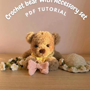 May include: A fuzzy brown crochet bear with a dark brown nose, wearing a yellow scarf. Accessories include a pink crochet bow, a white and green flower crown, and a beige crochet hat. The text reads: Crochet bear with Accessory set PDF TUTORIAL.