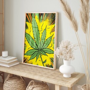 May include: A framed print of a green marijuana leaf on a yellow background with a comic book style explosion effect.