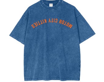 May include: A blue denim t-shirt with an orange graphic that reads "MOTOR CITY KITTIES" in an arc.
