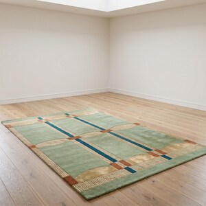 Puede incluir: Una alfombra rectangular con un dise&ntilde;o geom&eacute;trico. La alfombra presenta un fondo verde claro con un patr&oacute;n de rect&aacute;ngulos y l&iacute;neas azules, beige y &oacute;xido. Est&aacute; colocada sobre un suelo de madera.