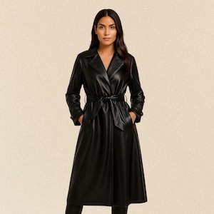 Könnte beinhalten: Ein langer, schwarzer Trenchcoat mit einem Gürtel in der Taille und einem klassischen Reverskragen. Der Mantel hat lange Ärmel und Taschen. Das Model trägt den Mantel. Der Mantel ist aus lederähnlichem Material.