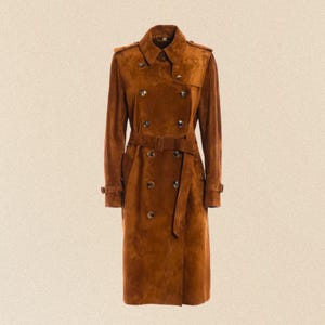 May include: A brown suede trench coat with a double-breasted design. The coat features a belt at the waist, buttoned cuffs, and a classic collar. The coat's length is approximately 127 cm.