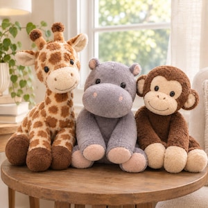 May include: A plush giraffe with brown spots, a grey plush hippopotamus, and a brown plush monkey sitting side by side. Each stuffed animal features a soft, textured fabric, embroidered facial details, and rounded limbs, presented as a trio.