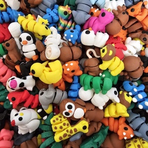 Könnte beinhalten: Eine Sammlung kleiner, bunter Tierfiguren aus Plastik. Die Figuren sind in verschiedenen Posen und umfassen eine Giraffe, einen Pinguin, einen Affen, ein Einhorn, eine Raupe und eine Vielzahl anderer Tiere.