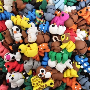 Puede incluir: Una colección de figuritas de plástico coloridas, pequeñas y de varios animales, incluyendo un pingüino, una jirafa, un unicornio, un ciervo, una tortuga, una serpiente, un pájaro y un gato. Las figuritas miden aproximadamente 5 cm de alto y están hechas de un plástico suave y flexible.